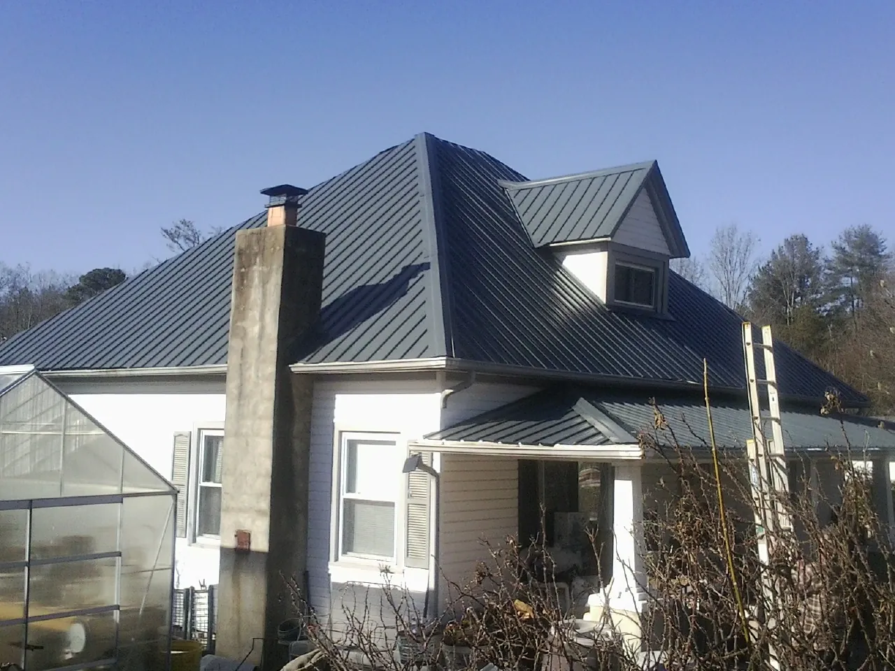 Dark blue standing seam metal roof on a white farmhouse with dormer — Slate & Tile Roof Repair by Roofing Brothers in El Sobrante