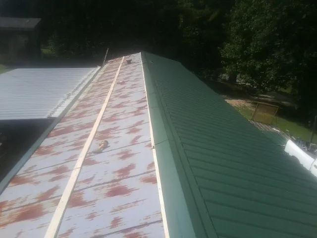 Old rusted panels beside newly installed green metal roofing — Wind Damage Roof Repair by Roofing Brothers in El Sobrante