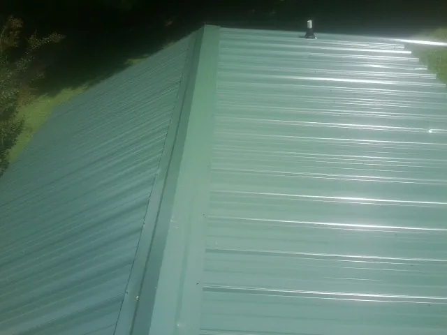 New green metal panels meeting at the ridge of a roof — Flat Roof Repair work by our crew in El Sobrante