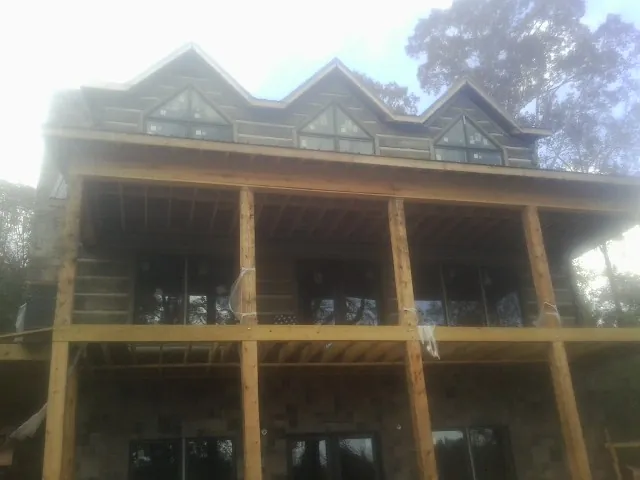 Dormers and porch framing on a large log home under construction — Roof Coating work by our crew in El Sobrante