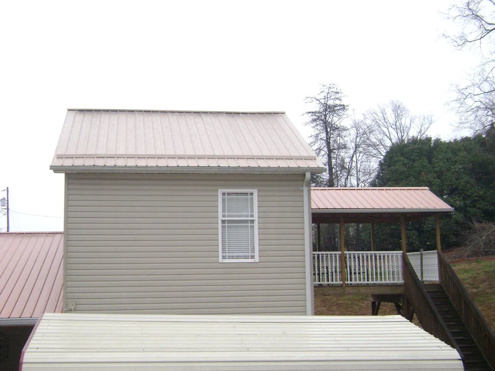 Tan metal roofs on a two story addition and attached porch, from a Roof Replacement job in El Sobrante