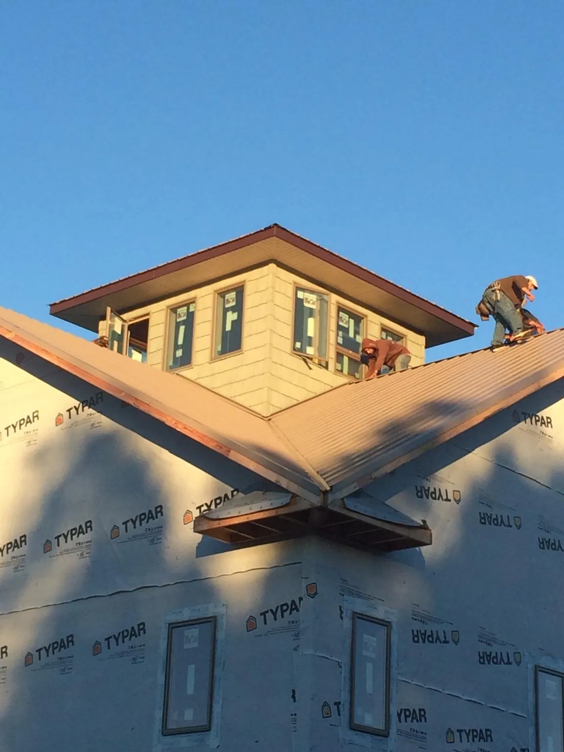 Roofers working around a rooftop cupola on a new metal roof at sunset — Roof Waterproofing in El Sobrante by Roofing Brothers